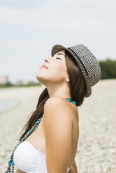 Porträt einer jungen Frau mit Hut, die sich am Strand entspannt - UUF001220