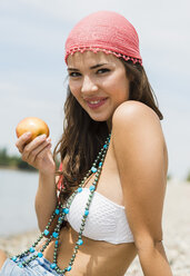 Porträt einer jungen Frau mit Apfel am Strand - UUF001282