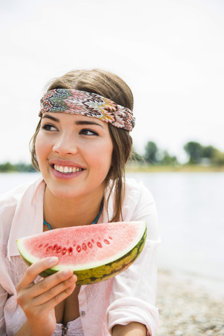 Porträt einer jungen Frau, die am Strand eine Wassermelone isst, lizenzfreies Stockfoto
