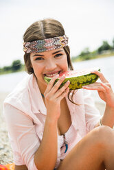 Porträt einer jungen Frau, die am Strand eine Wassermelone isst - UUF001288