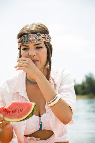 Porträt einer jungen Frau, die am Strand eine Wassermelone isst, lizenzfreies Stockfoto