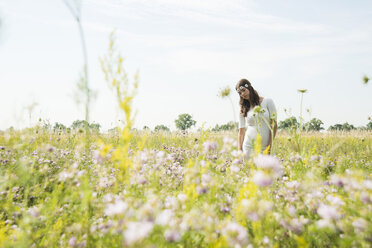 Porträt einer jungen Frau, die auf einer Blumenwiese steht - UUF001240