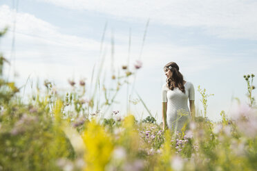 Portrait of young woman standing on flower meadow - UUF001244