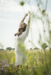 Happy young woman standing on flower meadow - UUF001246