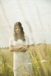 Portrait of young woman with crossed arms standing on flower meadow - UUF001253