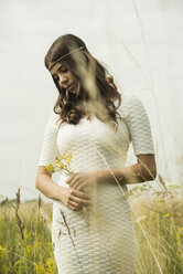 Young daydreaming woman standing on flower meadow - UUF001255