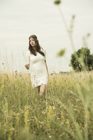 Porträt einer jungen Frau, die auf einer Blumenwiese spazieren geht, lizenzfreies Stockfoto
