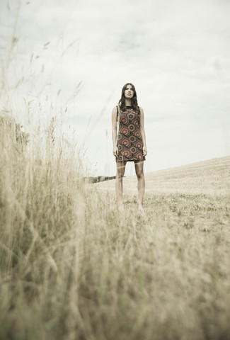 Junge Frau steht auf einer abgeernteten Wiese, lizenzfreies Stockfoto
