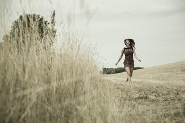 Young woman running on a harvested meadow - UUF001320