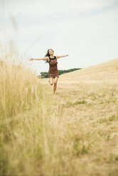 Young woman running on a harvested meadow - UUF001323