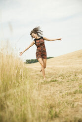 Young woman running on a harvested meadow - UUF001324