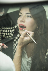 Female visagiste applying lipstick on young woman's lips - UUF001326