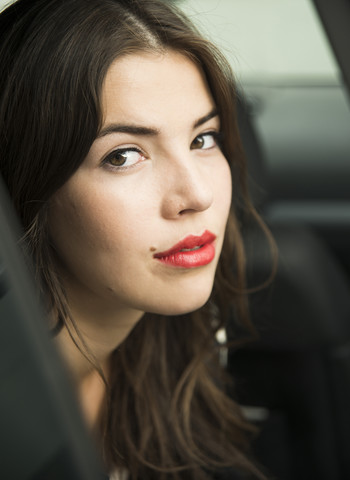 Porträt einer jungen Frau mit roten Lippen, die im Auto sitzt, lizenzfreies Stockfoto