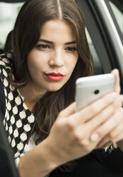 Portrait of young woman sitting in car taking a selfie with her smartphone - UUF001331