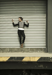 Young woman posing in front of roller shutter - UUF001341