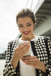Porträt einer lächelnden jungen Frau mit Smartphone - UUF001344