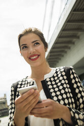 Porträt einer lächelnden jungen Frau mit Smartphone - UUF001345