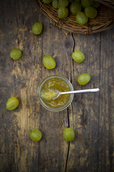 Jar of gooseberry jam and organic gooseberries on dark wood, elevated view - LVF001574