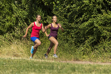 Zwei junge Frauen joggen auf einem Feldweg - STSF000440