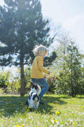 Boy playing with Jack Russel Terrier puppy in garden - MJF001303