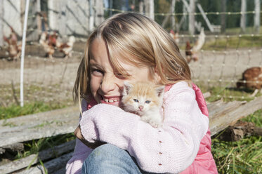 Glückliches Mädchen, das ein Kätzchen umarmt - HHF004833