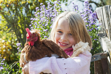 Glückliches Mädchen, das eine Henne umarmt - HHF004840