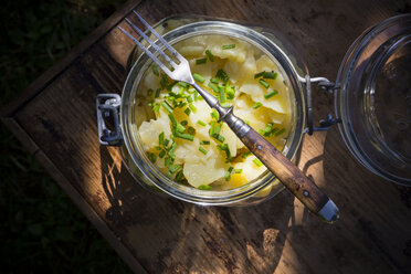 Preserving jar of Swabian potato salad and fork on wood, elevated view - LVF001595