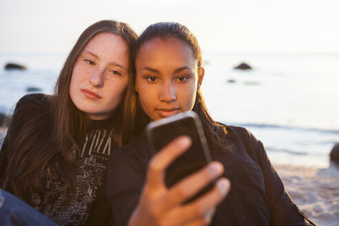 Deutschland, Rügen, Zwei junge Freundinnen mit Smartphone am Strand - OJF000053