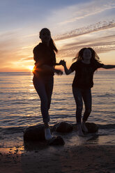 Deutschland, Rügen, Zwei junge Freundinnen am Strand bei Sonnenuntergang - OJF000057