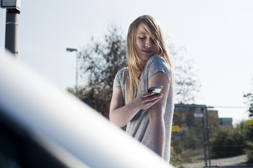 Blonde junge Frau mit Mobiltelefon im Freien - FEXF000100