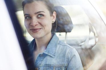 Lächelnde junge Frau auf dem Rücksitz eines Autos - FEXF000094