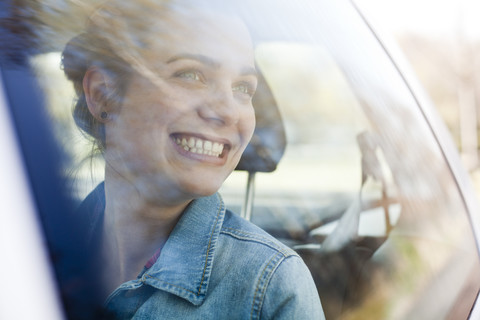 Lächelnde junge Frau auf dem Rücksitz eines Autos, lizenzfreies Stockfoto