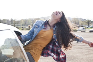 Exuberant young woman leaning out of car window - FEXF000123
