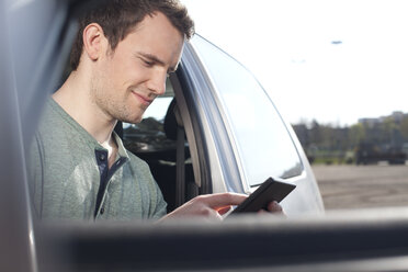 Junger Mann benutzt Mobiltelefon im Auto - FEXF000124