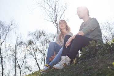 Relaxed young couple sitting on meadow - FEXF000126