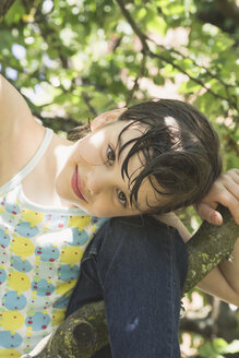 Porträt eines lächelnden kleinen Mädchens, das auf einen Baum klettert - LVF001587