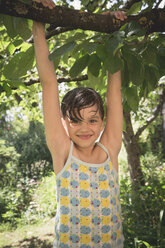Portrait of smiling little girl climbing on tree - LVF001589