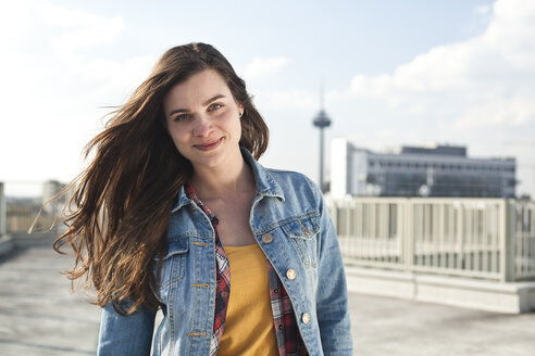 Germany, North Rhine-Westphalia, Cologne, portrait of smiling young woman standing on parking level - FEXF000133