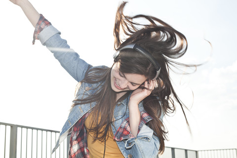 Porträt einer glücklichen jungen Frau, die mit Kopfhörern Musik hört, lizenzfreies Stockfoto