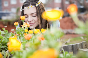 Porträt einer lächelnden jungen Frau, die sich an Blumen erfreut - FEXF000143