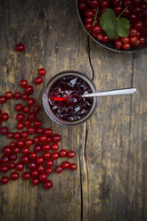 Marmeladenglas mit Johannisbeergelee, Schale und roten Johannisbeeren, Ribes rubrum, auf Holztisch, Draufsicht - LVF001602