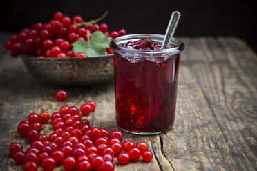 Marmeladenglas mit Johannisbeergelee, Schale und roten Johannisbeeren, Ribes rubrum, auf Holztisch - LVF001603