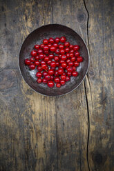 Bowl of red currants, Ribes rubrum, on dark wooden table, elevated view - LVF001608
