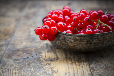 Bowl of red currants, Ribes rubrum, on dark wooden table, partial view - LVF001609