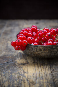 Bowl of red currants, Ribes rubrum, on dark wooden table, partial view - LVF001610