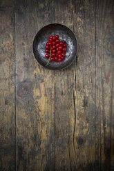 Bowl of red currants, Ribes rubrum, on dark wooden table, elevated view - LVF001614