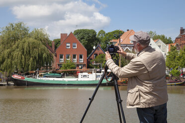 Deutschland, Niedersachsen, Leer, älterer Mann, der mit seiner Kamera den Museumshafen fotografiert - WIF000895