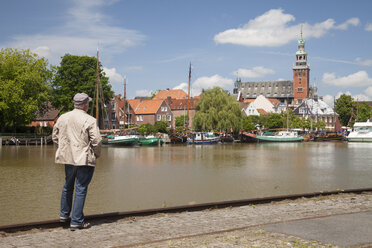 Germany, Lower Saxony, Leer, senior man looking at city with museum harbour in front - WIF000898