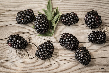 Blackberries and a leaf on wooden table, elevated view - SARF000722