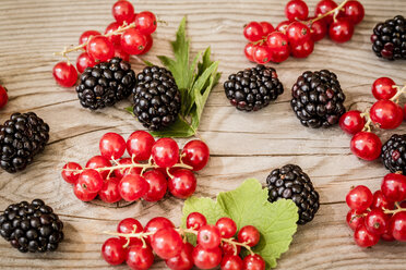 Red currants, blackberries and leaves on wooden table, elevated view - SARF000723